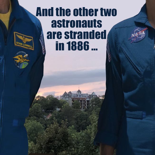 Between a male and a female astronaut clad in blue flightsuits is the distant image of the Crescent Hotel in Eureka Springs, Arkansas at dusk.